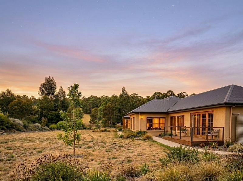Rough paddock beside a single-storey rural home at dusk, before landscaping